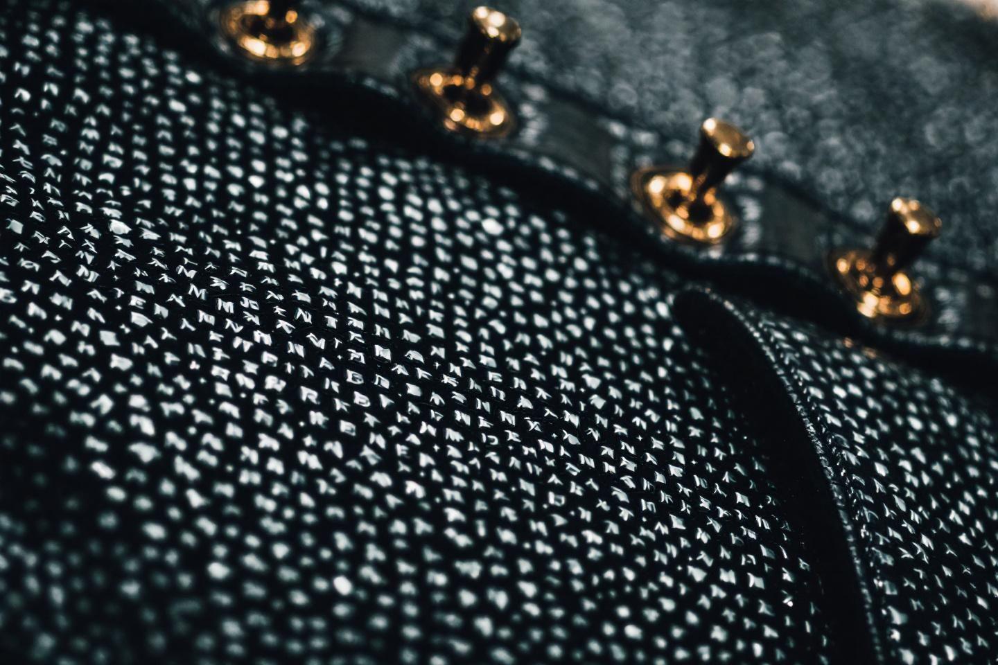 Gros plan de tissu noir texturé avec boutons métalliques dorés